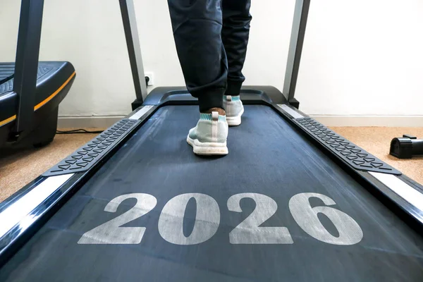Üzerinde 2026 yazısıyla koşu bandında yürüyen biri. Yeni yıl fitness sağlıklı bir yaşam tarzı ve yeni yıl için yeni fitness hedefleri.