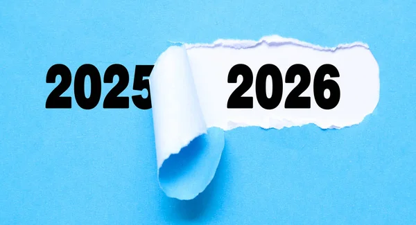 Yırtık mavi kağıt üzerinde 2025 'ten 2026' ya geçiş konsepti. 2026 Yırtık Kâğıtla Ortaya Çıktı