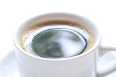 Sütlü kahveyi beyaz bir masada köpüklü bir bardakla kapat.