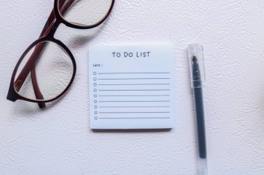 Kitaplar, bardaklar, saatler ve kahveyle çevrili masa üzerinde liste yapmak için. Tamamlanacak görevlerin kontrol listesi. İş planlaması, tasarım ve hatırlatma. Bir tablodaki numaraların listesini ve listesini yapmak için.