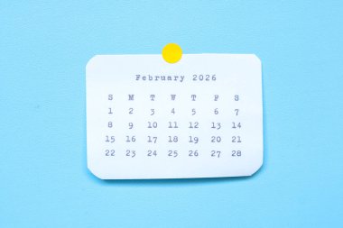 Şubat 2026 'da mavi arka plana yapıştırılmış bir kağıt çıkartması. Mavi arkaplana yapıştırılmış bir Şubat 2026 çıkartması. Asgari ve temiz takvim kavramı.