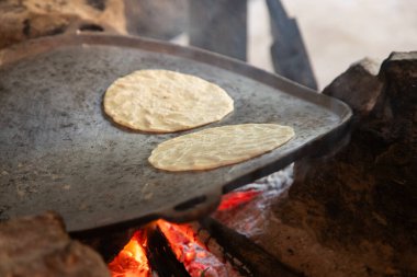 Geleneksel mısır tortillaları açık odun ateşinde kuyrukluyıldızda pişiyor.