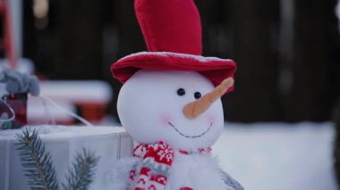 Karlı bir Kış Günü 'nde Kırmızı Şapkalı Yumuşak Kardan Adam Dekorasyonu ve Açık Hava Atkısı Şenlikli Sıcak Tatil Sahnesi ve Sığ Saha Derinliği