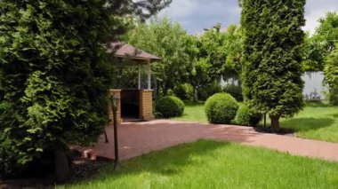 Tuğla avlusu ve manikürlü çalıları olan rahat bahçe çardağı, yeşil çimenli ve ağaçlı huzurlu arka bahçe manzarası