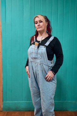 Güzel, neşeli, kızıl, Latin, yetişkin bir kadının portresi. Davranışlarıyla poz veriyor ve kot pantolon giyiyor. Ona stüdyosunda birkaç boya fırçası eşlik ediyor.                               