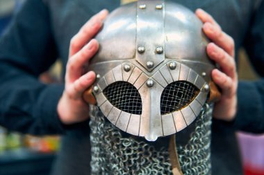 Bir ortaçağ savaşçısının miğferi ellerinden sergileniyor. Oldukça detaylı, zincirli ve çok iyi korunmuş bir metal miğfer. Bir ortaçağ savaşçısının kasklı elleri..                               