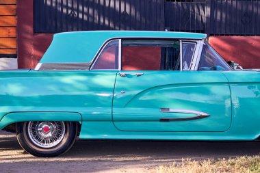 Kırmızı ışıkları olan güzel bir antika turkuaz araba. İyi bakımlı ve iyi boyanmış bir araç, yenilenmiş. Yan taraftan görüldü. Gün batımında parka park ettim, doğal ışıkla..