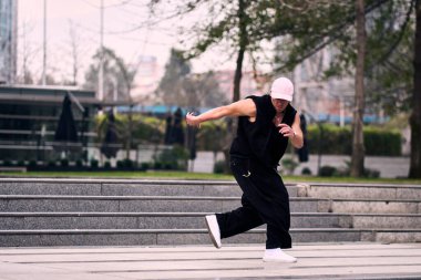 Bazı ofis binalarının dışında enerjik bir şekilde break dans yapan genç bir adam, rahat kıyafetler giyen, bir sürü tavırlı, hareketli ve iyi enerjili. Sokak dansı, serbest stil, modern dans..