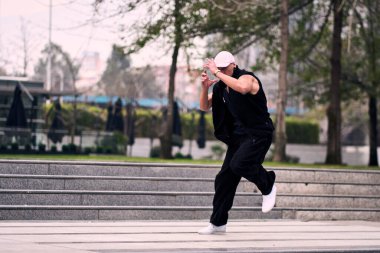 Bazı ofis binalarının dışında enerjik bir şekilde break dans yapan genç bir adam, rahat kıyafetler giyen, bir sürü tavırlı, hareketli ve iyi enerjili. Sokak dansı, serbest stil, modern dans..