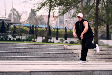 Bazı ofis binalarının dışında enerjik bir şekilde break dans yapan genç bir adam, rahat kıyafetler giyen, bir sürü tavırlı, hareketli ve iyi enerjili. Sokak dansı, serbest stil, modern dans..