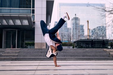 Genç yetişkinler bazı binaların önünde coşkuyla dans eder, amuda kalkarlar, kot pantolon ve şehir kıyafetleri giyerler, bir sürü tavır, hareket ve iyi enerji. Sokak dansı, serbest stil, modern dans..