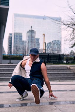 Genç yetişkinler binaların önünde coşkuyla dans eder, yerde döner, kot pantolon ve şehir kıyafetleri giyer. Bir sürü tavır, hareket ve iyi enerji. Sokak dansı, serbest stil, modern dans..