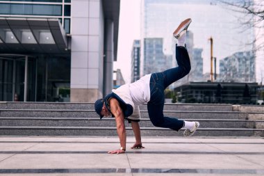 Genç yetişkinler binaların önünde coşkuyla dans eder, yerde döner, kot pantolon ve şehir kıyafetleri giyer. Bir sürü tavır, hareket ve iyi enerji. Sokak dansı, serbest stil, modern dans..