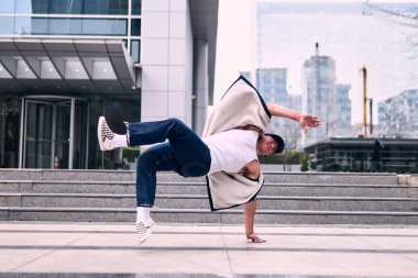 Genç yetişkinler binaların önünde coşkuyla dans eder, yerde döner, kot pantolon ve şehir kıyafetleri giyer. Bir sürü tavır, hareket ve iyi enerji. Sokak dansı, serbest stil, modern dans..
