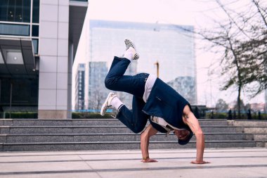 Genç yetişkinler bazı binaların önünde coşkuyla dans eder, amuda kalkarlar, kot pantolon ve şehir kıyafetleri giyerler, bir sürü tavır, hareket ve iyi enerji. Sokak dansı, serbest stil, modern dans..