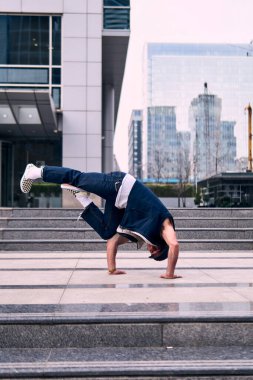 Genç yetişkinler bazı binaların önünde coşkuyla dans eder, amuda kalkarlar, kot pantolon ve şehir kıyafetleri giyerler, bir sürü tavır, hareket ve iyi enerji. Sokak dansı, serbest stil, modern dans..