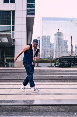 Genç, zinde bir yetişkin coşkuyla break dans yapıyor, zıplıyor, ritim tutuyor. Kot pantolon ve şehir kıyafetleri giymişti. Bir sürü tavır, hareket ve iyi enerji. Sokak dansı, serbest stil, modern dans..