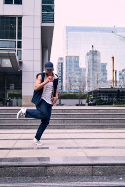 Genç, zinde bir yetişkin coşkuyla break dans yapıyor, zıplıyor, ritim tutuyor. Kot pantolon ve şehir kıyafetleri giymişti. Bir sürü tavır, hareket ve iyi enerji. Sokak dansı, serbest stil, modern dans..