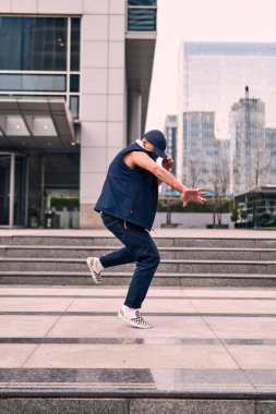 Genç, zinde bir yetişkin coşkuyla break dans yapıyor, zıplıyor, ritim tutuyor. Kot pantolon ve şehir kıyafetleri giymişti. Bir sürü tavır, hareket ve iyi enerji. Sokak dansı, serbest stil, modern dans..