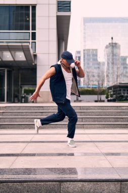 Genç, zinde bir yetişkin coşkuyla break dans yapıyor, zıplıyor, ritim tutuyor. Kot pantolon ve şehir kıyafetleri giymişti. Bir sürü tavır, hareket ve iyi enerji. Sokak dansı, serbest stil, modern dans..