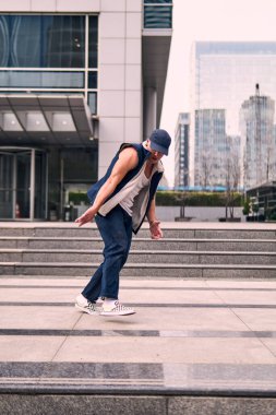 Genç, zinde bir yetişkin coşkuyla break dans yapıyor, zıplıyor, ritim tutuyor. Kot pantolon ve şehir kıyafetleri giymişti. Bir sürü tavır, hareket ve iyi enerji. Sokak dansı, serbest stil, modern dans..