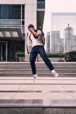 Genç, zinde bir yetişkin coşkuyla break dans yapıyor, zıplıyor, ritim tutuyor. Kot pantolon ve şehir kıyafetleri giymişti. Bir sürü tavır, hareket ve iyi enerji. Sokak dansı, serbest stil, modern dans..