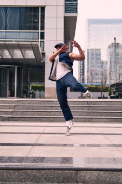 Genç, zinde bir yetişkin coşkuyla break dans yapıyor, zıplıyor, ritim tutuyor. Kot pantolon ve şehir kıyafetleri giymişti. Bir sürü tavır, hareket ve iyi enerji. Sokak dansı, serbest stil, modern dans..