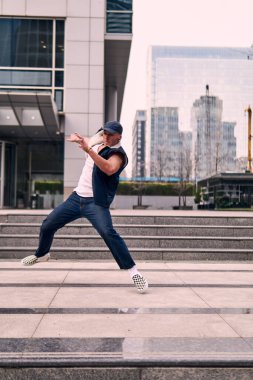 Genç, zinde bir yetişkin coşkuyla break dans yapıyor, zıplıyor, ritim tutuyor. Kot pantolon ve şehir kıyafetleri giymişti. Bir sürü tavır, hareket ve iyi enerji. Sokak dansı, serbest stil, modern dans..