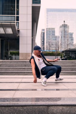 Genç yetişkinler binaların önünde coşkuyla dans eder, yerde döner, kot pantolon ve şehir kıyafetleri giyer. Bir sürü tavır, hareket ve iyi enerji. Sokak dansı, serbest stil, modern dans..