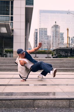 Genç yetişkinler binaların önünde coşkuyla dans eder, yerde döner, kot pantolon ve şehir kıyafetleri giyer. Bir sürü tavır, hareket ve iyi enerji. Sokak dansı, serbest stil, modern dans..