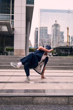 Genç yetişkinler binaların önünde coşkuyla dans eder, yerde döner, kot pantolon ve şehir kıyafetleri giyer. Bir sürü tavır, hareket ve iyi enerji. Sokak dansı, serbest stil, modern dans..