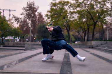 Genç yetişkinler coşkuyla dans eder, amuda kalkar ve yerde döner. Kot pantolon, sokak kıyafeti ve şapka giyiyor. Bir sürü tavır, hareket ve iyi enerji. Sokak dansı, serbest stil ve modern dans..