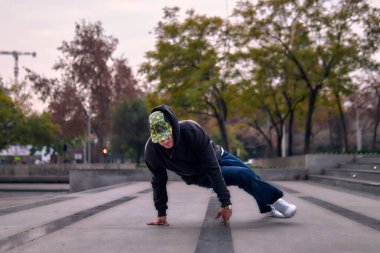 Genç yetişkinler coşkuyla dans eder, amuda kalkar ve yerde döner. Kot pantolon, sokak kıyafeti ve şapka giyiyor. Bir sürü tavır, hareket ve iyi enerji. Sokak dansı, serbest stil ve modern dans..