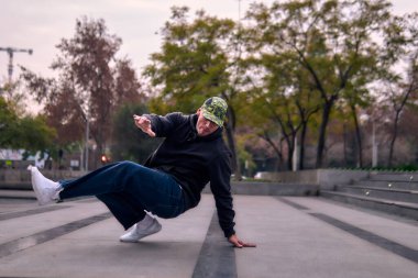 Genç yetişkinler coşkuyla dans eder, amuda kalkar ve yerde döner. Kot pantolon, sokak kıyafeti ve şapka giyiyor. Bir sürü tavır, hareket ve iyi enerji. Sokak dansı, serbest stil ve modern dans..