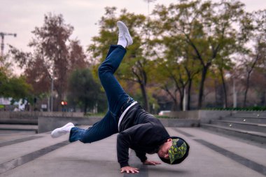 Genç yetişkinler coşkuyla dans eder, amuda kalkar ve yerde döner. Kot pantolon, sokak kıyafeti ve şapka giyiyor. Bir sürü tavır, hareket ve iyi enerji. Sokak dansı, serbest stil ve modern dans..