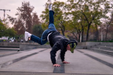 Genç yetişkinler coşkuyla dans eder, amuda kalkar ve yerde döner. Kot pantolon, sokak kıyafeti ve şapka giyiyor. Bir sürü tavır, hareket ve iyi enerji. Sokak dansı, serbest stil ve modern dans..