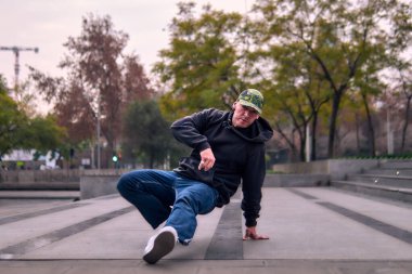 Genç yetişkinler coşkuyla dans eder, amuda kalkar ve yerde döner. Kot pantolon, sokak kıyafeti ve şapka giyiyor. Bir sürü tavır, hareket ve iyi enerji. Sokak dansı, serbest stil ve modern dans..