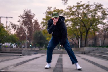 Genç yetişkinler coşkuyla dans eder, yürür, dinlenir ve kötü çocuk pozları verir. Kot pantolon, sokak kıyafeti ve şapka giyiyor. Bir sürü tavır, hareket ve iyi enerji. Serbest stil ve modern dans.