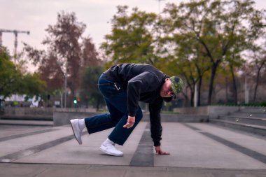 Genç yetişkinler coşkuyla dans eder, yürür, dinlenir ve kötü çocuk pozları verir. Kot pantolon, sokak kıyafeti ve şapka giyiyor. Bir sürü tavır, hareket ve iyi enerji. Serbest stil ve modern dans.