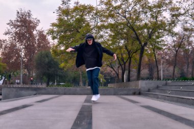 Genç yetişkinler coşkuyla dans eder, yürür, dinlenir ve kötü çocuk pozları verir. Kot pantolon, sokak kıyafeti ve şapka giyiyor. Bir sürü tavır, hareket ve iyi enerji. Serbest stil ve modern dans.