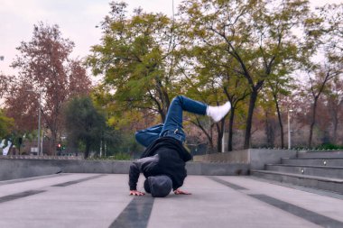 Genç yetişkinler coşkuyla dans eder, amuda kalkar ve yerde döner. Kot pantolon, sokak kıyafeti ve şapka giyiyor. Bir sürü tavır, hareket ve iyi enerji. Sokak dansı, serbest stil ve modern dans..