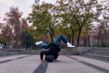 Genç yetişkinler coşkuyla dans eder, amuda kalkar ve yerde döner. Kot pantolon, sokak kıyafeti ve şapka giyiyor. Bir sürü tavır, hareket ve iyi enerji. Sokak dansı, serbest stil ve modern dans..