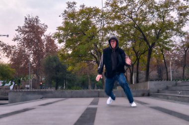 Genç yetişkinler coşkuyla dans eder, yürür, dinlenir ve kötü çocuk pozları verir. Kot pantolon, sokak kıyafeti ve şapka giyiyor. Bir sürü tavır, hareket ve iyi enerji. Serbest stil ve modern dans.