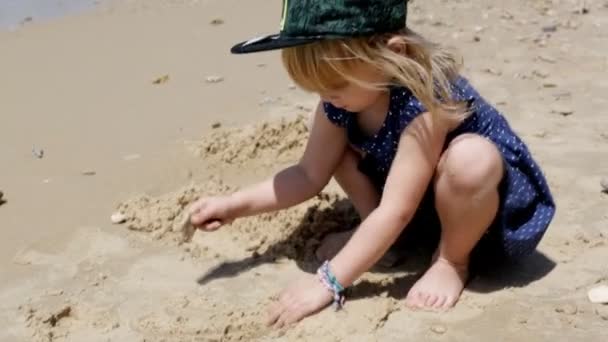 Criança brincando na praia, menina se divertindo com um castelo de areia — Vídeo de Stock