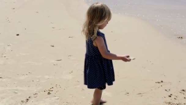 Beautiful a little girl in a white dress running along coastline. — Stock Video
