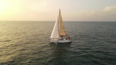 Yelkenli tekneleri, Boracay, Filipinler 'deki hava manzaralı deniz yüzeyinin üstünde renkli bir günbatımı. Su yüzeyine yansıyan güneş.