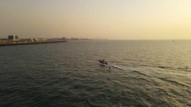 Günbatımı manzaralı bir tekneden sonra hava gözlemi yapan wakeboardçu.