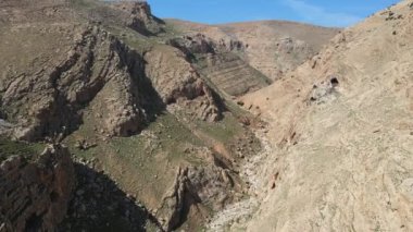 İsrail 'in mavi gökyüzü, Judea ve Samarya bölgesindeki Binyamin Bölgesi' ndeki kuru vadi ve dağların insansız hava aracı görüntüleri. Bitkilerle dolu İsrail çöl kanyonu. 4K dağları arasındaki insansız hava aracı