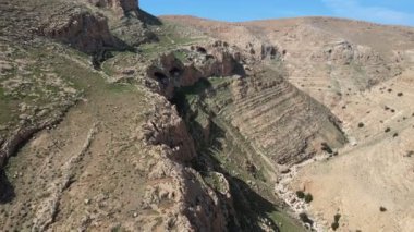 İsrail 'in Judean Çölü' nde Mitzpe Dani yakınlarındaki Judean çöl dağları. Kış yağmurlarının ardından arka planda birkaç bulut var.