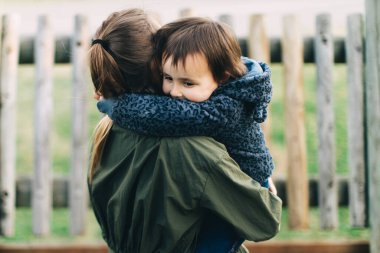 Anne ve kızı parkta birbirlerine sarılıp oynuyorlar.